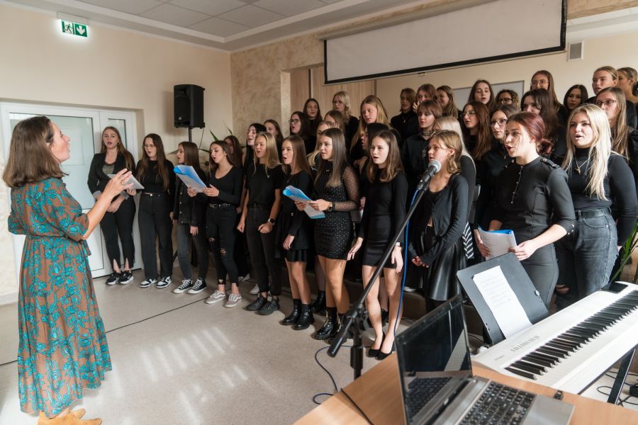 grupa dziewcząt śpiewa przed nimi stoi kbieta drygent