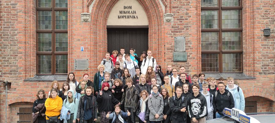 grupa młodzieży na schodach domu kopernika w toruniu