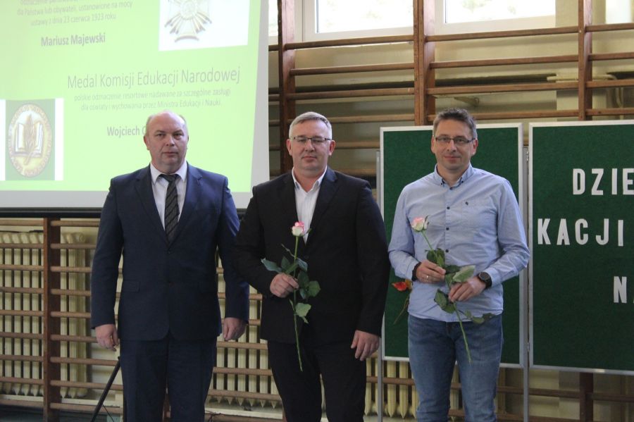 trzech mężczyzn stoi obook siebie dwóch z nich trzyma różę