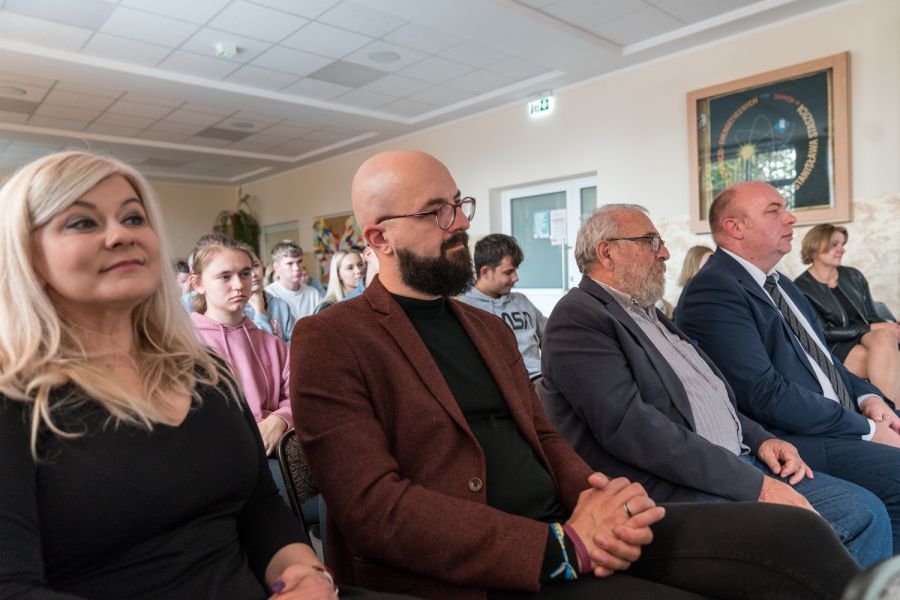 cztery osoby siedż na krzesłach w pierwszym rzędzie w tle kolejne osoby