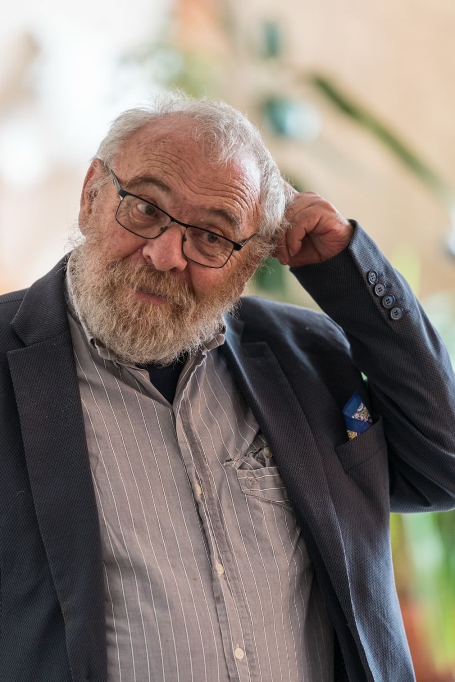 mężczyzna w okularach i siwa broa drapie sie po głowie