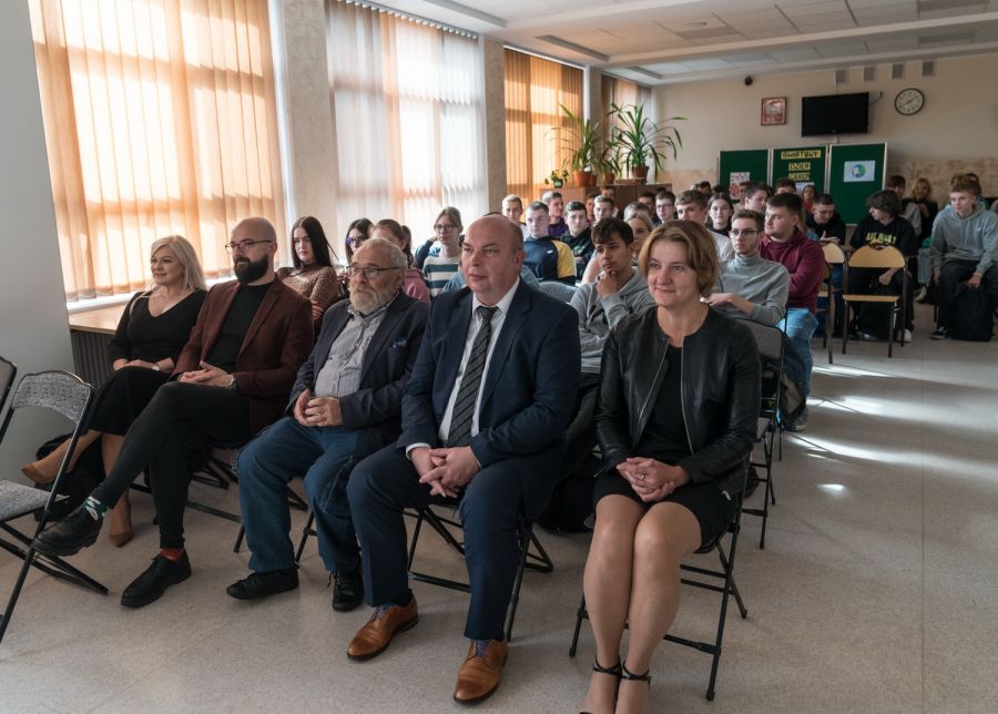grupa osób siedząca na krzesłach ustawionych w rzędach