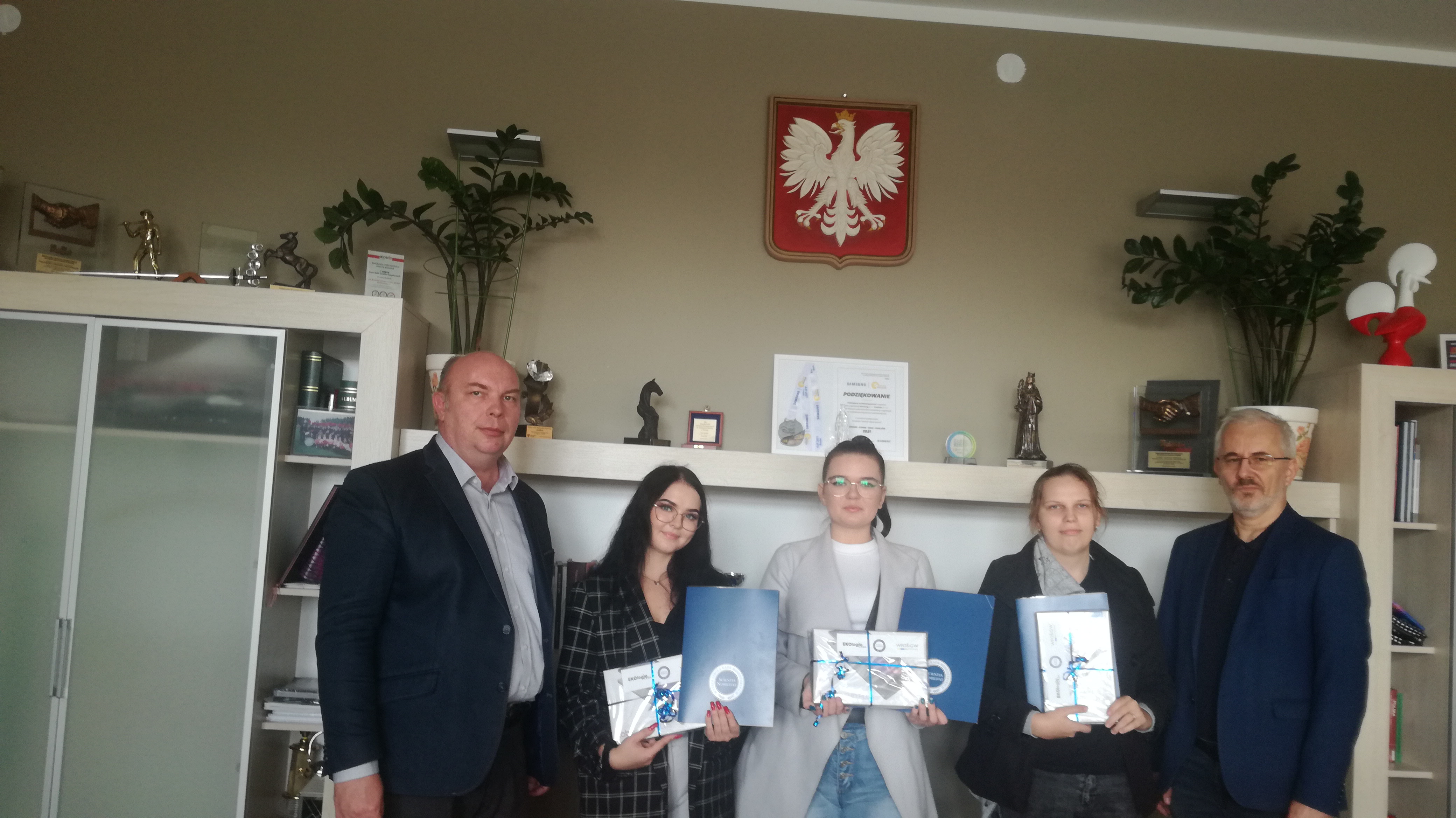 Trzy dziewczyny oraz dwóch mężczyz stoi przodem do obiektywu, dziewczyny trzymają w rękach nagrody